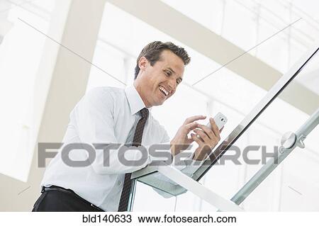 Caucasian businessman using cell phone on office staircase View Large Photo Image Stock Image - Caucasian businessman using cell phone on office staircase. Fotosearch