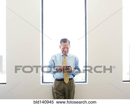Stock Photography - Caucasian businessman using cell phone in office. Fotosearch