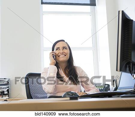 Caucasian businesswoman talking on cell phone at desk View Large Photo Image Stock Photo - Caucasian businesswoman talking on cell phone at desk. Fotosearch