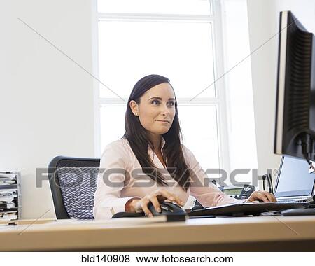 Stock Photo - Caucasian businesswoman working on computer at desk. Fotosearch