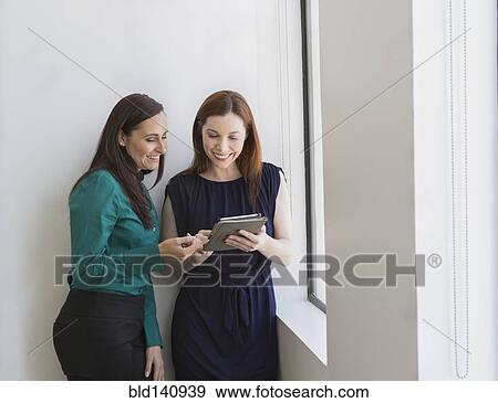 Stock Photo - Caucasian businesswomen using digital tablet at office window. Fotosearch