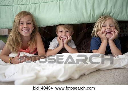 Caucasian children laying under bed View Large Photo Image Picture - Caucasian children laying under bed. Fotosearch