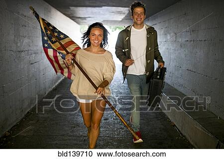 Caucasian couple carrying American flag and boom box in tunnel View Large Photo Image Stock Image - Caucasian couple carrying American flag and boom box in tunnel. Fotosearch