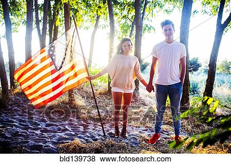 Stock Photo - Caucasian couple holding American flag in park. Fotosearch
