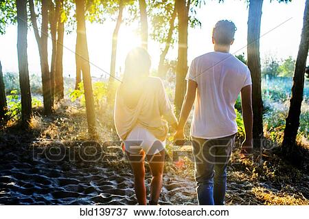 Caucasian couple holding hands in park View Large Photo Image Stock Photo - Caucasian couple holding hands in park. Fotosearch