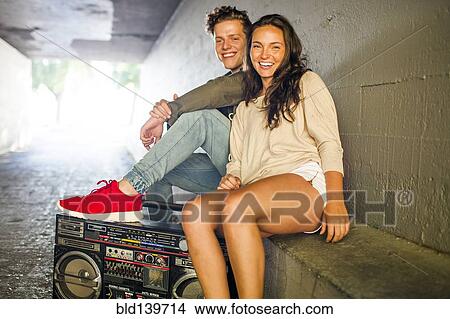 Picture - Caucasian couple listening to boom box in tunnel. Fotosearch