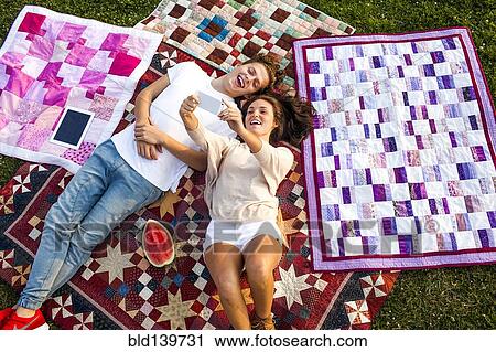 Caucasian couple taking selfie on blankets in park View Large Photo Image Stock Image - Caucasian couple taking selfie on blankets in park. Fotosearch