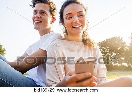 Caucasian couple using cell phone outdoors View Large Photo Image Stock Photo - Caucasian couple using cell phone outdoors. Fotosearch