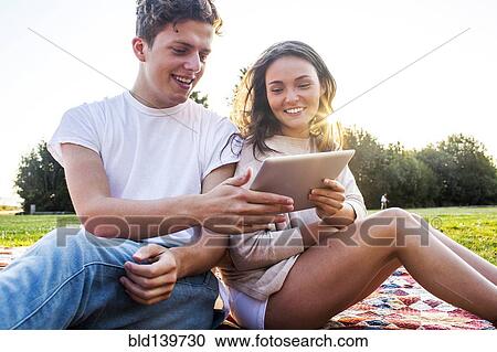 Caucasian couple using digital tablet together in park View Large Photo Image Stock Image - Caucasian couple using digital tablet together in park. Fotosearch