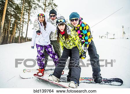 Picture - Caucasian couples snowboarding posing on snowy slope. Fotosearch