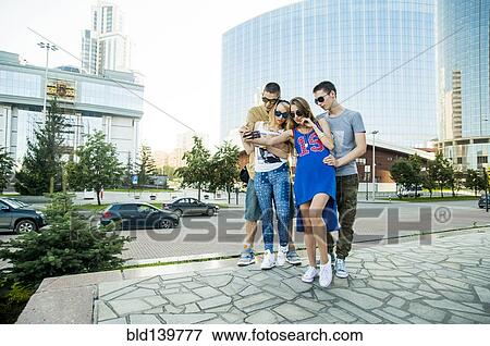 Stock Photo - Caucasian couples taking selfie together in city. Fotosearch
