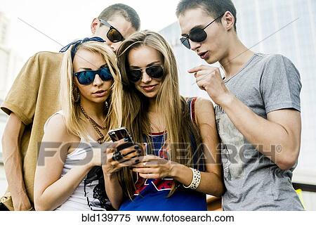 Stock Photography - Caucasian couples using cell phone outdoors. Fotosearch