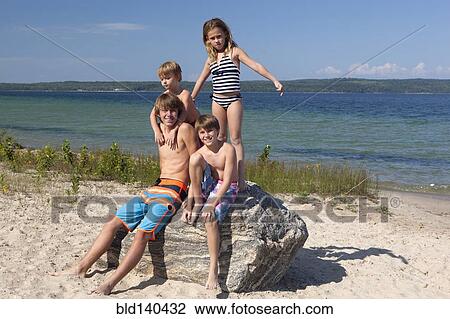 Caucasian cousins standing on rock at beach View Large Photo Image Stock Image - Caucasian cousins standing on rock at beach. Fotosearch