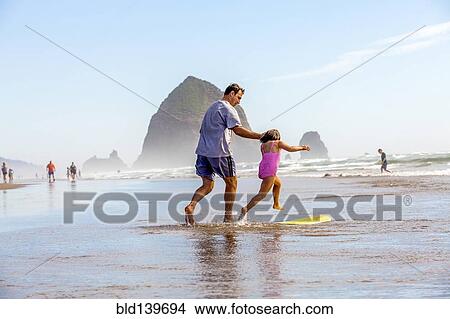 Caucasian father and daughter playing in surf on beach View Large Photo Image Picture - Caucasian father and daughter playing in surf on beach. Fotosearch