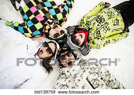 Stock Photo - Caucasian friends laying in snow. Fotosearch