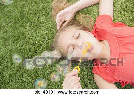 Caucasian girl blowing bubbles on grassy lawn View Large Photo Image Stock Image - Caucasian girl blowing bubbles on grassy lawn. Fotosearch