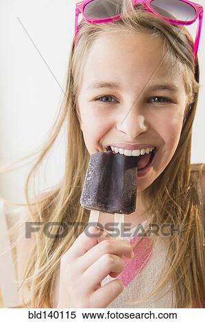 Stock Photography - Caucasian girl eating grape popsicle. Fotosearch