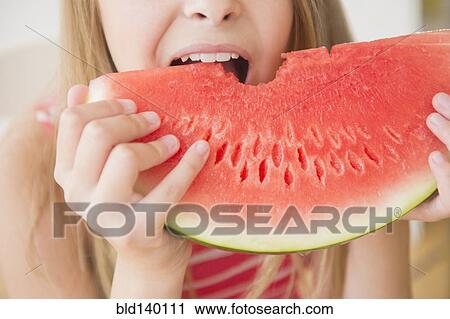 Stock Image - Caucasian girl eating large slice of watermelon. Fotosearch