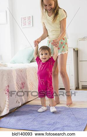 Caucasian girl helping toddler sister walk in bedroom View Large Photo Image Stock Image - Caucasian girl helping toddler sister walk in bedroom. Fotosearch