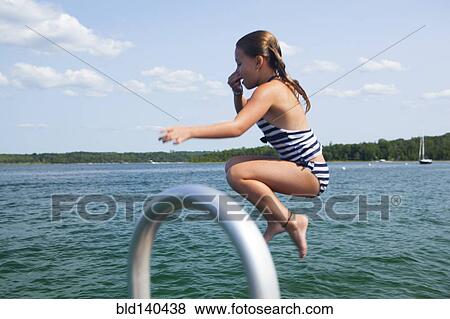 Stock Photo - Caucasian girl jumping into lake. Fotosearch