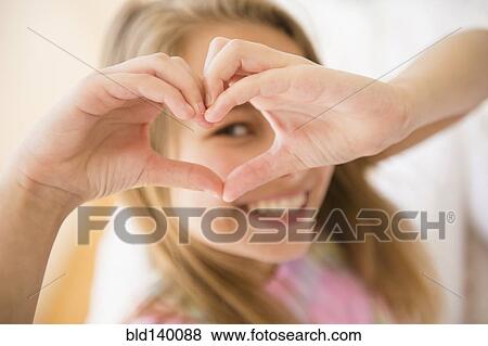 Stock Photo - Caucasian girl making heart shape with hands. Fotosearch