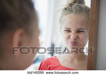 Stock Photo - Caucasian girl scrunching up her face in mirror. Fotosearch