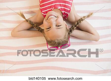 Stock Photography - Caucasian girl smiling on beach towel. Fotosearch