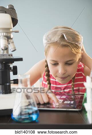 Stock Photo - Caucasian girl using digital tablet in science lab. Fotosearch