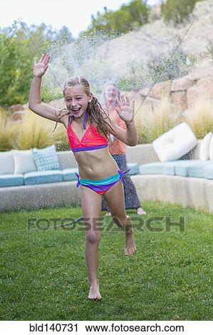 Caucasian grandmother spraying granddaughter with water in backyard View Large Photo Image Stock Image - Caucasian grandmother spraying granddaughter with water in backyard. Fotosearch