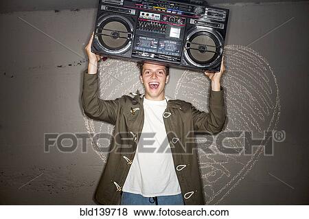 Stock Photo - Caucasian man holding boom box near chalk heart on wall. Fotosearch