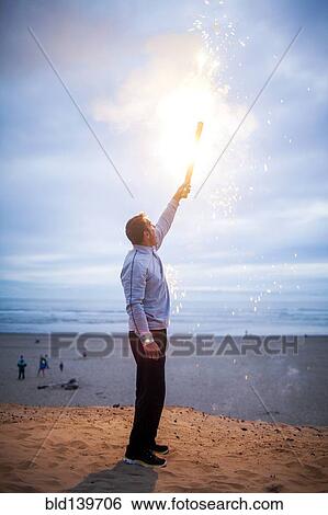 Caucasian man holding fireworks on beach View Large Photo Image Stock Photograph - Caucasian man holding fireworks on beach. Fotosearch