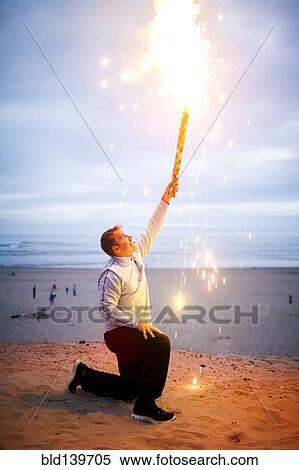 Caucasian man holding fireworks on beach View Large Photo Image Stock Photography - Caucasian man holding fireworks on beach. Fotosearch