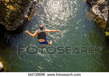 Caucasian man jumping off rocks into ocean View Large Photo Image Stock Photograph - Caucasian man jumping off rocks into ocean. Fotosearch