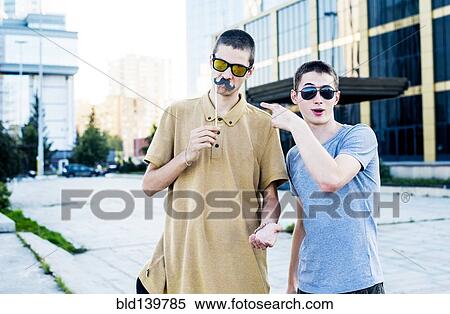 Stock Photography - Caucasian men playing with fake mustaches in city. Fotosearch