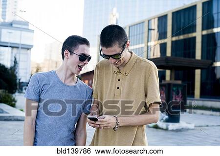 Stock Photograph - Caucasian men using cell phone in city. Fotosearch