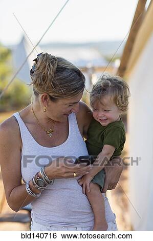 Stock Photograph - Caucasian mother and baby son using cell phone. Fotosearch