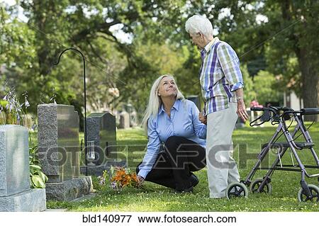 Caucasian mother and daughter visiting grave in cemetery View Large Photo Image Stock Photo - Caucasian mother and daughter visiting grave in cemetery. Fotosearch