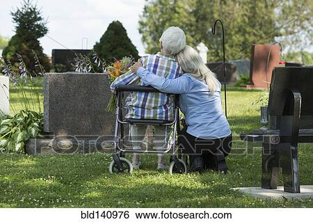 Stock Photograph - Caucasian mother and daughter visiting grave in cemetery. Fotosearch