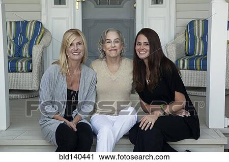 Stock Image - Caucasian mother and daughters smiling on front porch. Fotosearch