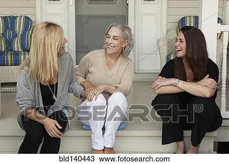 Stock Image - Caucasian mother and daughters smiling on front porch. Fotosearch