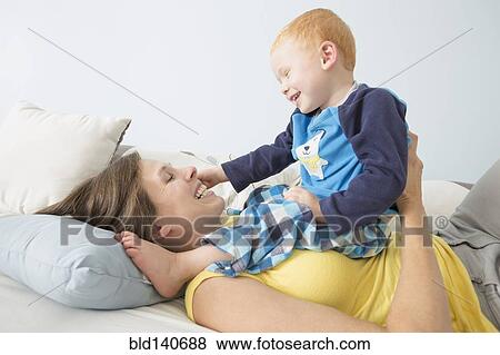 Stock Photo - Caucasian mother and son playing on bed. Fotosearch
