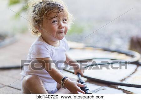 Stock Image - Caucasian toddler boy playing with hose. Fotosearch