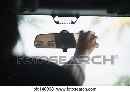 Stock Photo - Caucasian woman adjusting rear view mirror in car. Fotosearch