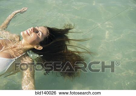 Stock Photograph - Caucasian woman floating in ocean. Fotosearch