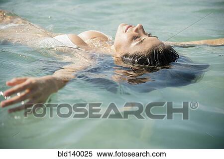 Stock Photography - Caucasian woman floating in ocean. Fotosearch