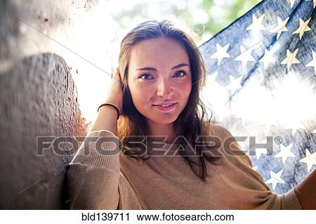 Stock Image - Caucasian woman holding American flag outdoors. Fotosearch