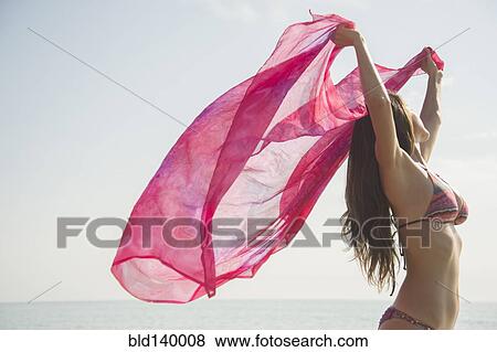 Caucasian woman holding fabric in wind at beach View Large Photo Image Stock Photo - Caucasian woman holding fabric in wind at beach. Fotosearch