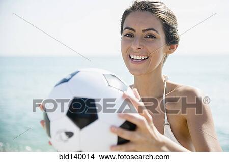 Picture - Caucasian woman holding soccer ball on beach. Fotosearch