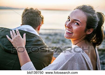 Stock Image - Caucasian woman relaxing with boyfriend on beach. Fotosearch
