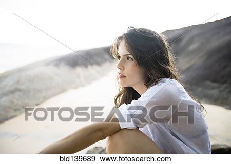 Stock Photo - Caucasian woman sitting on beach. Fotosearch